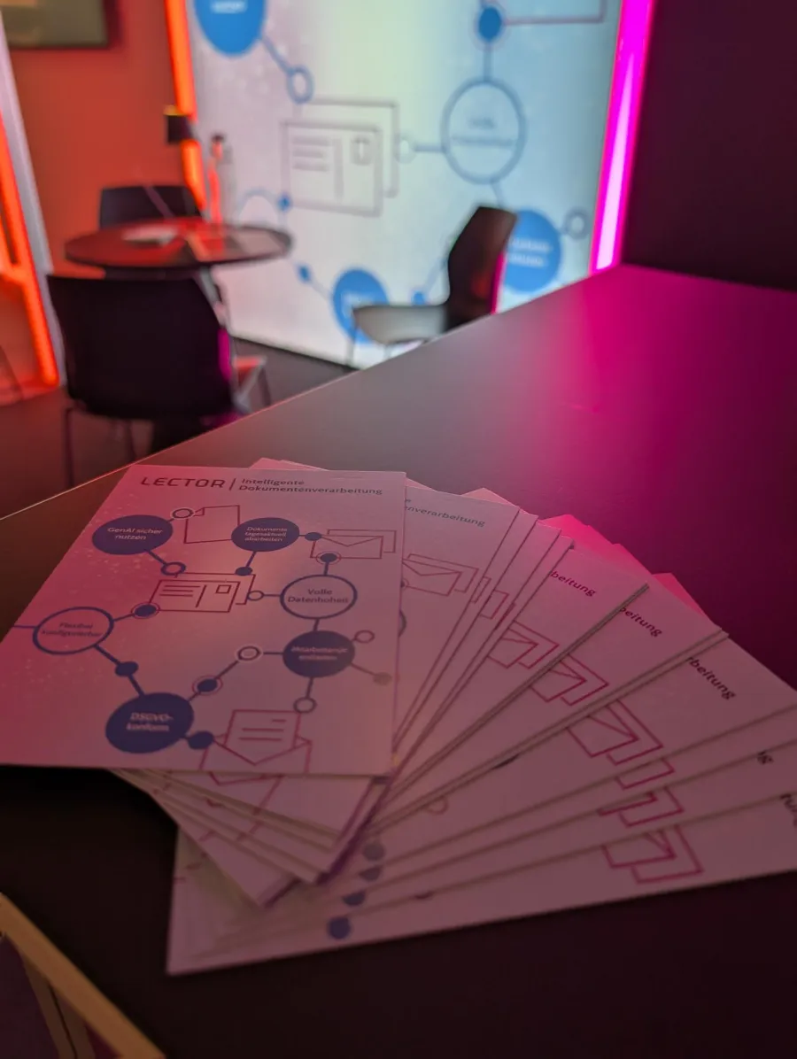 Aufgefächerte Lector-Flyer „Intelligente Dokumentenverarbeitung“ auf dem Tisch am Messestand, dahinter die beleuchtete Rückwand mit dem Prozessdiagramm